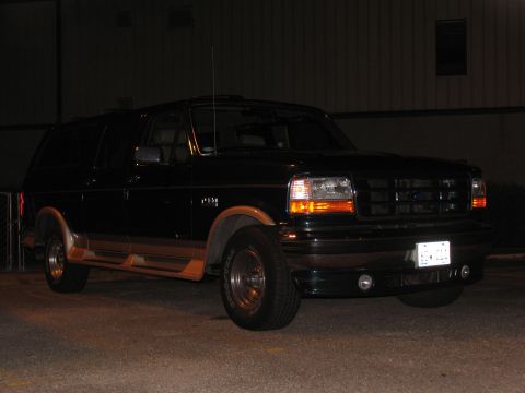 1995 Ford C-150 (Centurion Conversions) - This 1995 Ford C-150 (Centurion Conversions) is captured in a 3/4 front view, its black exterior with tan trim and a visible license plate.