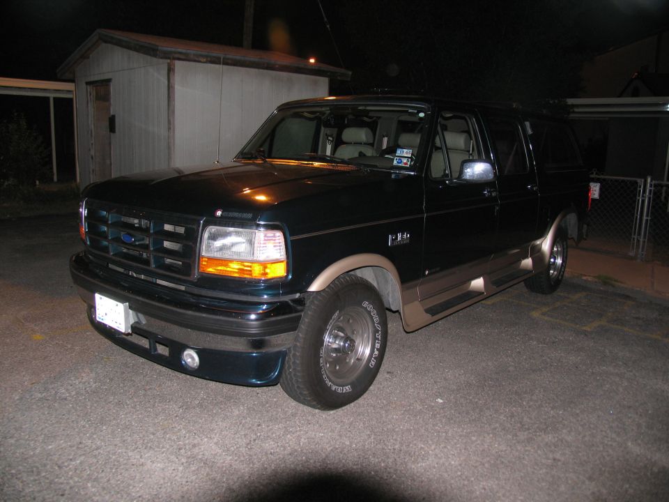 Dark green 1995 Ford C-150 conversion van with tan trim, 3/4 front view