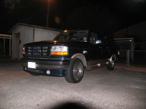 1995 Ford C-150 (Centurion Conversions) - A dark green Ford Bronco with tan trim is parked in a driveway at night.