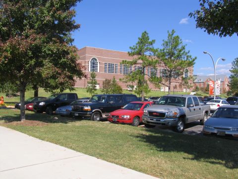 1995 Ford C-150 (Centurion Conversions) - A black Ford Bronco is parked in a lot with other vehicles under a clear blue sky.