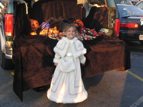 1995 Ford C-150 (Centurion Conversions) - A child dressed in a white costume stands in front of a truck bed decorated for a Halloween event.