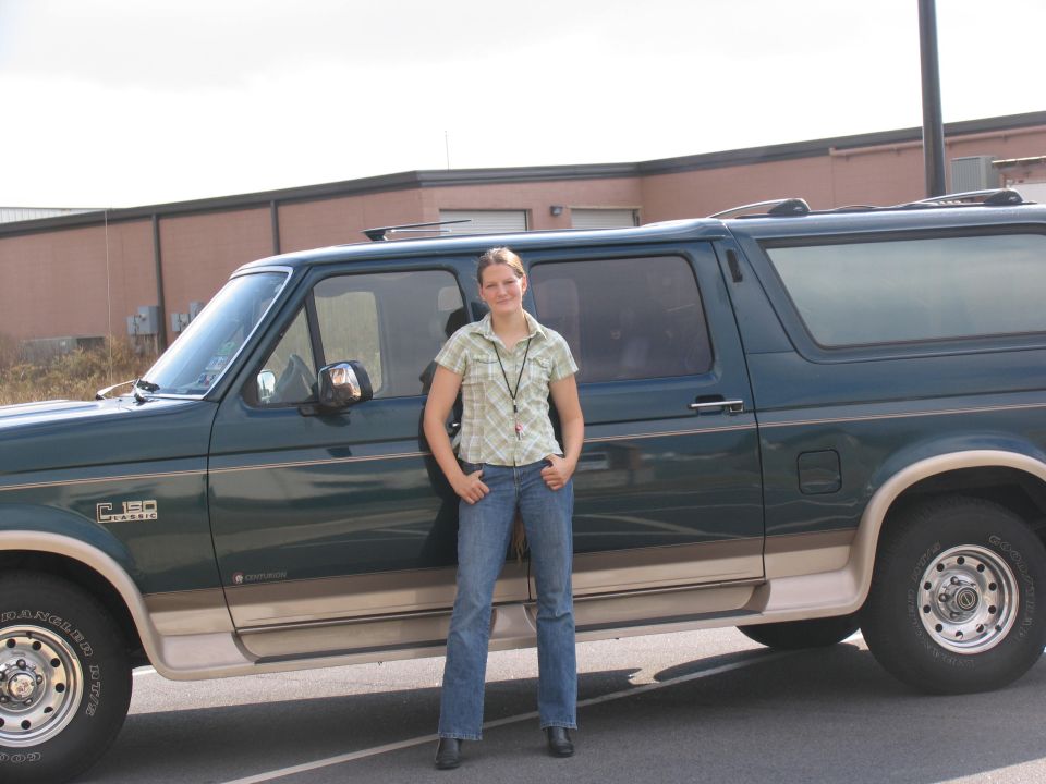 Dark green Ford Centurion SUV in side view with woman standing in front