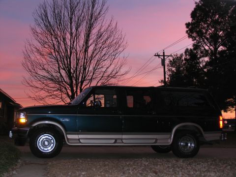 1995 Ford C-150 (Centurion Conversions) - An extended SUV, possibly a Centurion conversion, is seen parked outdoors during a colorful sunset.