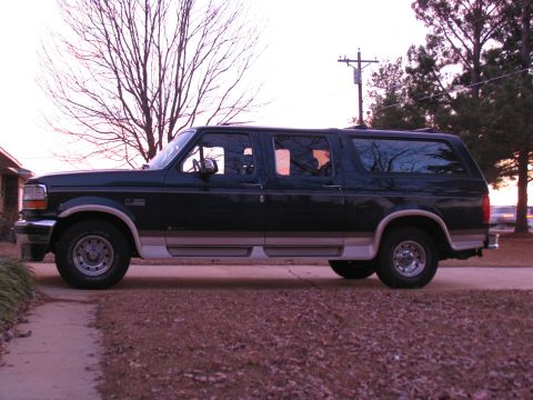 1995 Ford C-150 (Centurion Conversions) - Dark green Ford Bronco conversion with tan trim seen from the side.