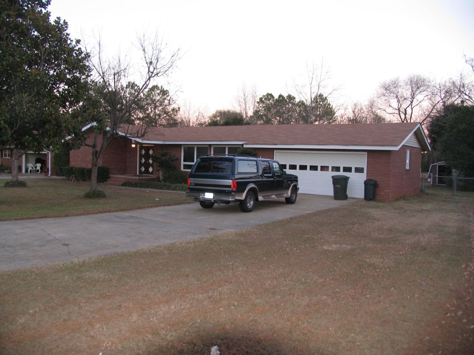 1995 Ford C-150 Centurion Conversions SUV parked in driveway next to a brick house with a garage