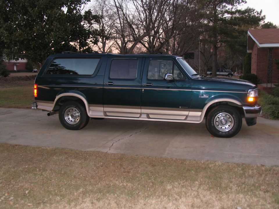 Green Ford Bronco SUV parked on a driveway. It has tan trim and running boards