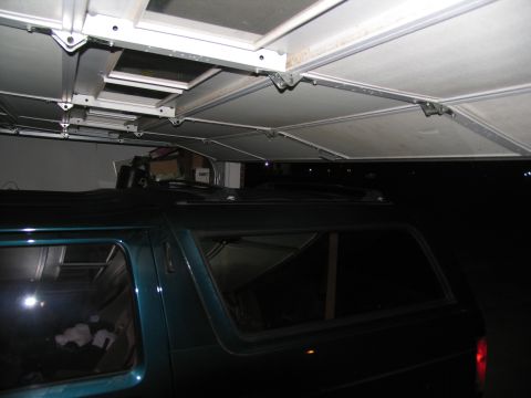 1995 Ford C-150 (Centurion Conversions) - A teal SUV is parked inside a garage, with the garage door mechanism visible above.