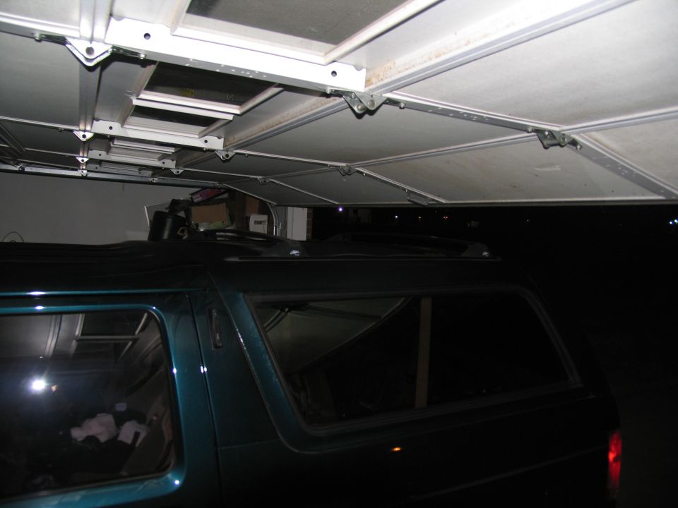 Teal SUV side view, parked under a garage door