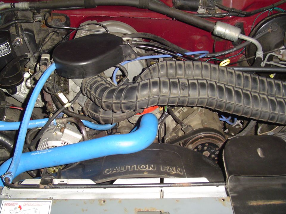 Engine bay with blue hoses and a 'CAUTION FAN' shroud