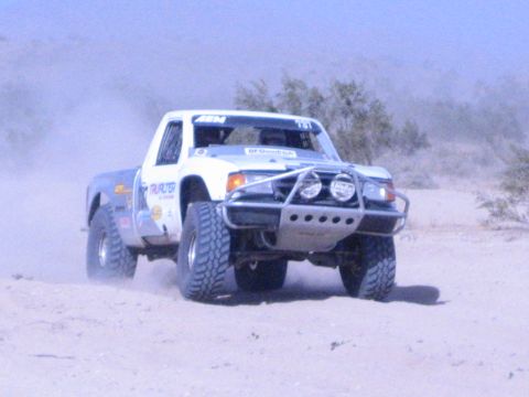 White off-road race truck with light pod racing on sandy desert course