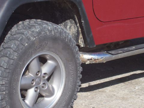 1998 Jeep TJ - A red Jeep Wrangler's side profile, highlighting its off-road tire and corroded running board.