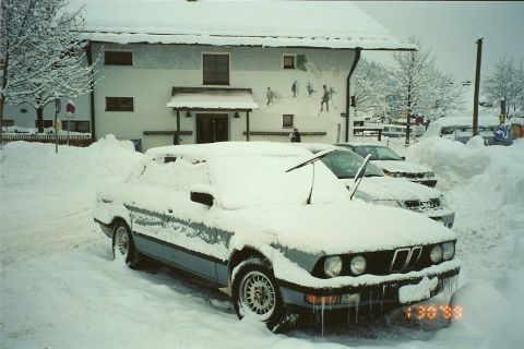 2003 Jeep TJ - A BMW E30 is partially buried in snow, with icicles forming on its front bumper. Another car is visible behind it, also covered in snow.