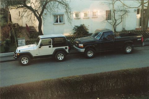 2003 Jeep TJ - Two vehicles, a Jeep TJ and a Ford pickup, are parked on a street in front of a house.