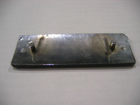 1985 Ford LTD Crown Victoria - A metal badge with mounting posts is shown from the back, with no visible text or identifying marks.