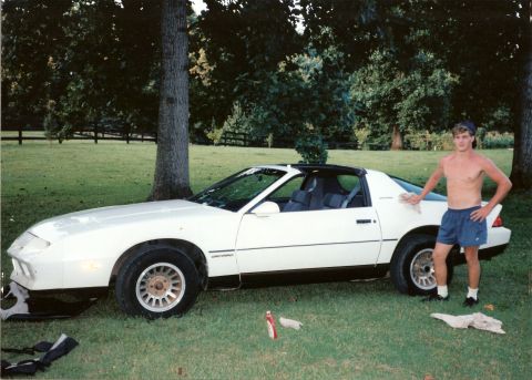 2003 Jeep TJ - Man poses with a white Chevrolet Camaro parked on a grassy lawn.