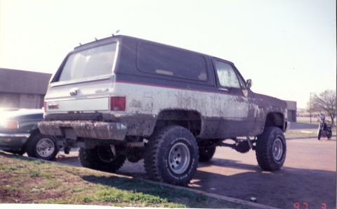 2003 Jeep TJ - This lifted GMC K5 Blazer is covered in mud, suggesting recent off-road activity.
