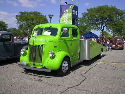 1973 Ford Ranchero - A bright green tow truck is parked on asphalt with other vehicles in the background.