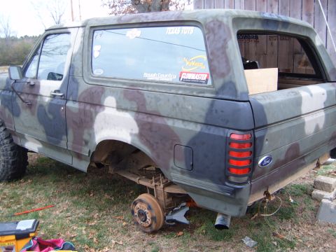 1988 Ford Bronco - This 1988 Ford Bronco is painted in camouflage and is missing a rear wheel, resting on a jack.