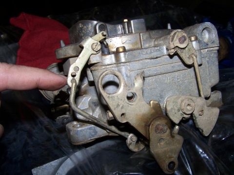 1979 Ford F-150 - A finger points to the linkage on a Weber carburetor, a key engine component.