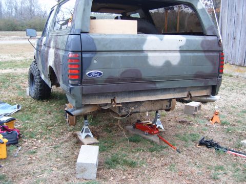 1988 Ford Bronco - A 1988 Ford Bronco, painted in camouflage, is raised on jack stands for maintenance.