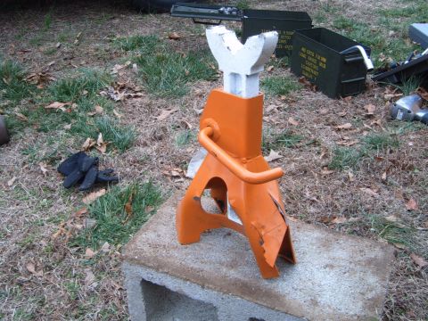 1988 Ford Bronco - A jack stand and two ammo cans sit on the ground outdoors.