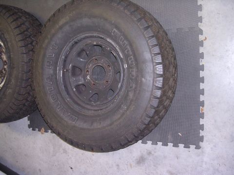 1985 Ford Bronco - Two tires are shown on a gray floor. One tire has the text "DAKOTA RVT" visible on its sidewall.