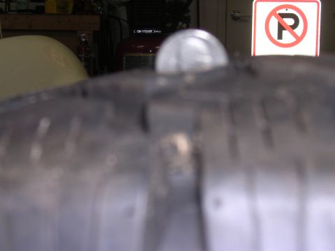 1985 Ford Bronco - A coin rests on a tire tread, with a no parking sign in the background.