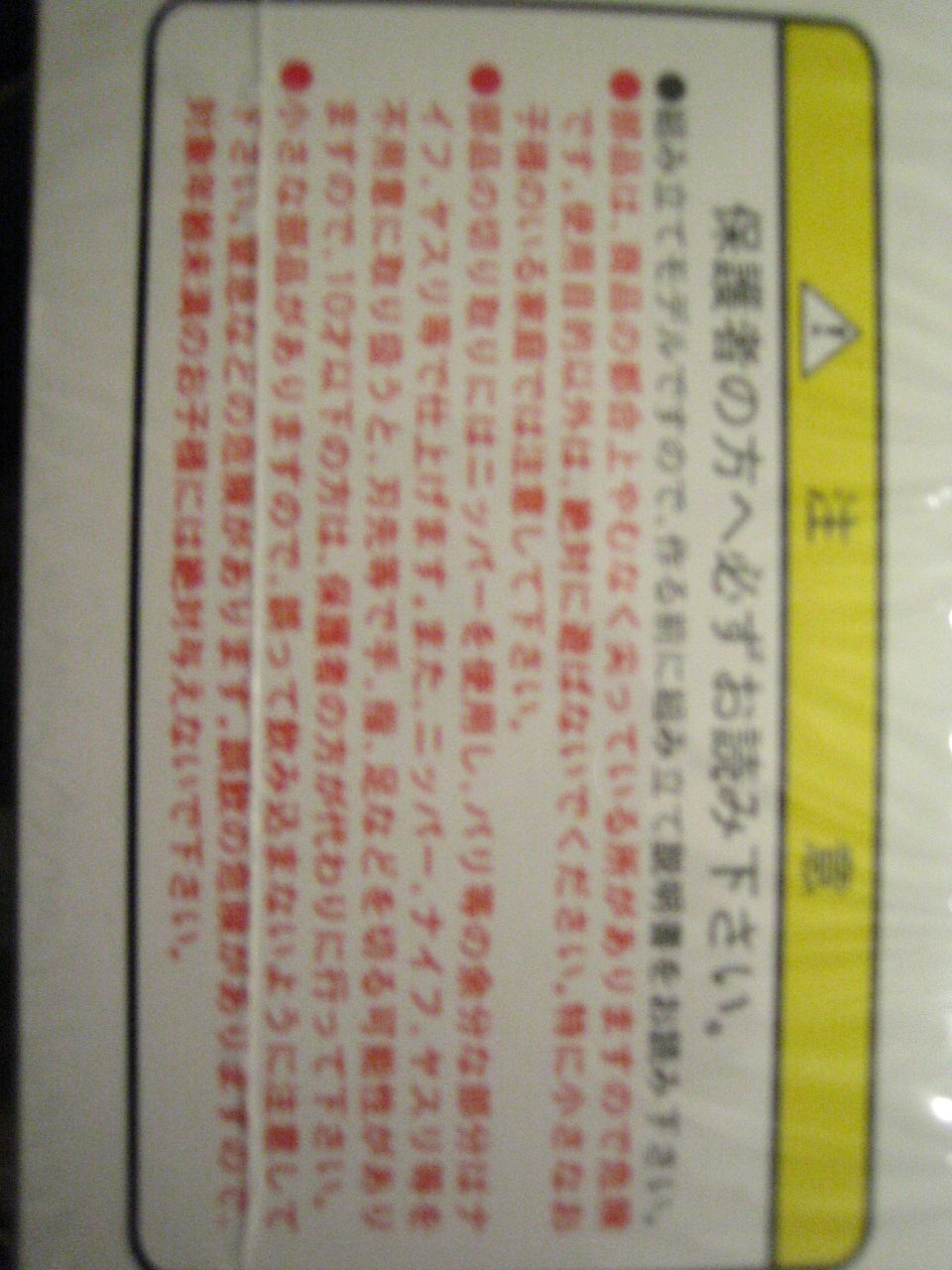 Rotated Japanese model-kit safety warning label, red text on white card