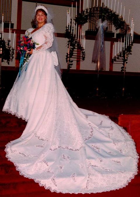 1985 Ford Bronco - Bride posing in a wedding dress with a long, ornate train and holding a bouquet.