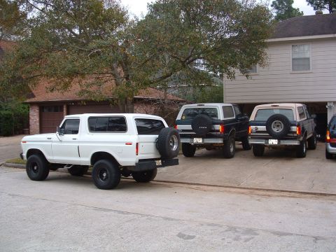 1993 Ford Bronco - Three Ford Broncos are parked in a driveway, with one white Bronco in the foreground.