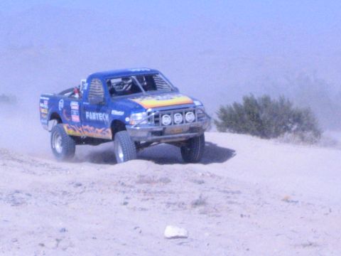 Blue off-road race truck with flame graphics and Fabtech decal on desert hill