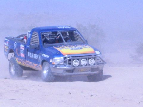 Blue Fabtech race truck 1018 with flame graphics on sandy desert course