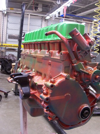 1988 Jeep Cherokee - Engine block with green valve cover and orange/red painted surfaces, mounted on a stand in a workshop.