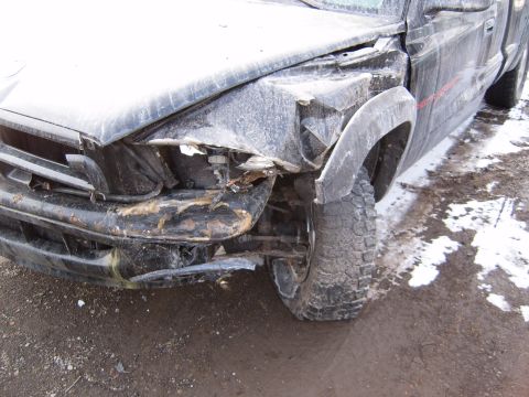 1993 Ford Bronco - The front end of a black truck is heavily damaged, with a crumpled fender and bumper visible.