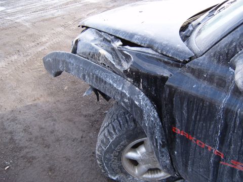1993 Ford Bronco - The front fender and hood of a black pickup truck are heavily damaged.