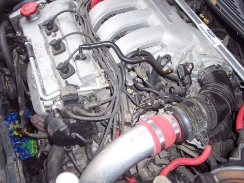 1995 Ford Probe - Engine bay details showing intake piping, spark plug wires, and distributor cap.