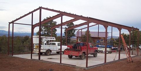 1986 Ford Ranger - Two trucks are parked inside a metal building under construction, with mountains in the background.