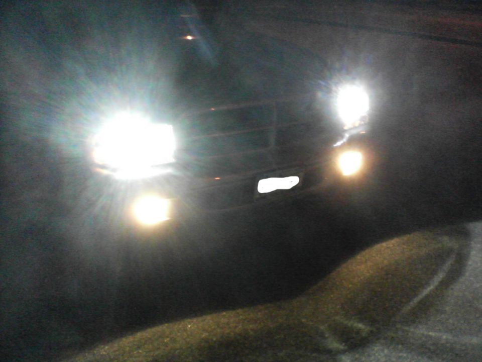 Front of dark SUV with bright headlights and fog lights on