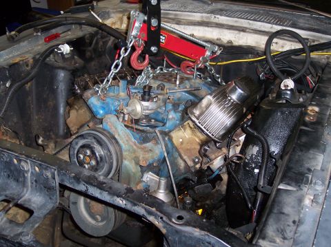 1967 Ford Mustang - Engine hoist suspended over the engine of a 1967 Ford Mustang, showing the blue engine block and chrome air cleaner.