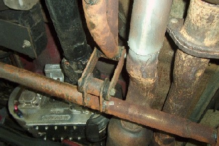 1977 Ford F-150 - Close-up of a vehicle's exhaust system and transmission, showing rusty pipes and metal parts.