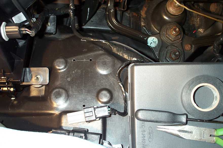 The holes drilled for the tach adapter. The pick used to pierce the grommet can be seen on the fusebox.