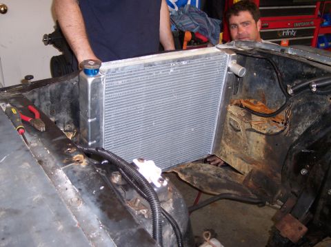 1967 Ford Mustang - A new radiator is being installed in the engine bay of a vehicle. Tools are present, suggesting ongoing work.