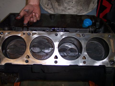 1967 Ford Mustang - Engine block with pistons showing wear. A mechanic's hand is visible above the block.