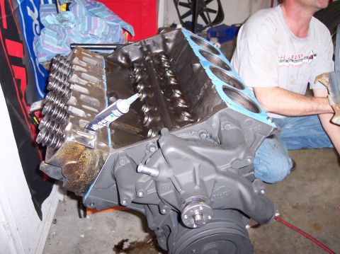 1967 Ford Mustang - Close-up of an engine block assembly with valve springs and sealant being applied during a repair or build.