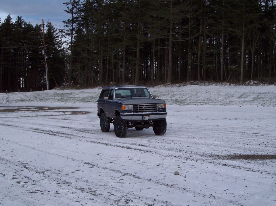 1987 Ford Bronco on snowy ground with trees in background