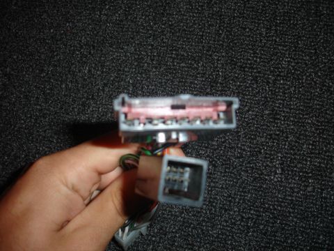 1993 Ford Taurus - Close-up of two electrical connectors for a car's audio system, held in a hand.