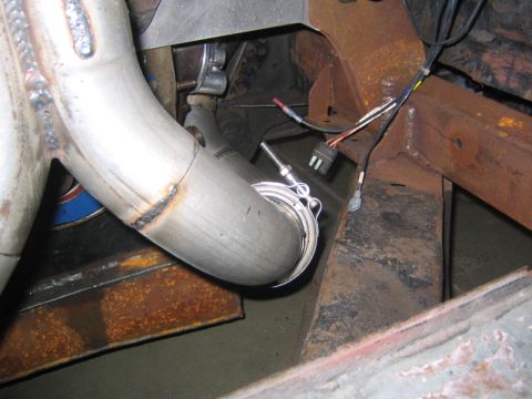 1969 Ford Mustang - Custom exhaust pipe with a sensor, attached to a rusty vehicle frame.