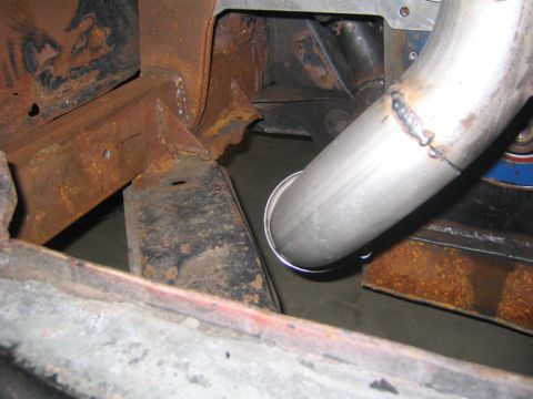 1969 Ford Mustang - A new exhaust pipe is being fitted to a heavily rusted vehicle frame, indicating a repair or modification project.