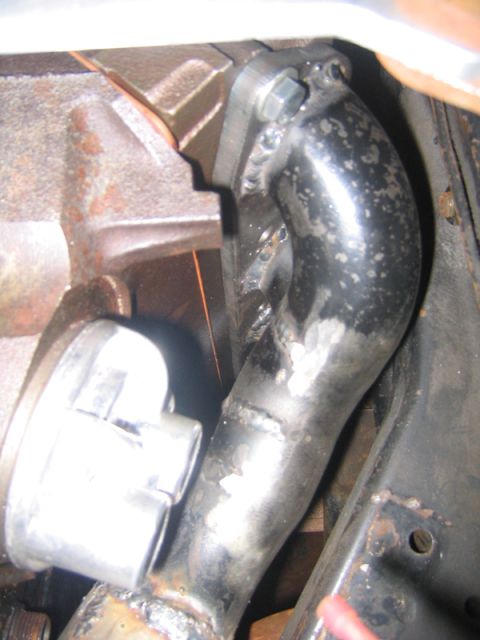 1969 Ford Mustang - Close-up of a custom exhaust pipe installation on an engine block.