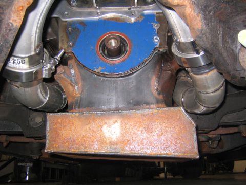1969 Ford Mustang - Close-up view of engine components, including exhaust pipes and a protective shield.